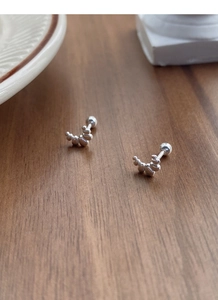 Detail of S999 silver croissant-shaped screw back earrings on dark wood surface