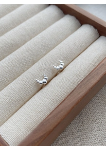 Macro shot of S999 silver croissant stud earrings in a premium wooden jewelry box