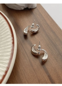 Macro view of S925 sterling silver drop U-shape earrings on dark wood surface