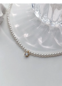 Dettaglio macro di una collana di perle in argento S925 con pendente in zircone lucido
