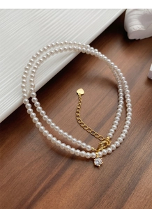 Dettaglio della collana di perle a due fili con ciondolo in zircone e cuore in metallo oro