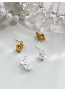 Detailed view of matte gold and silver S925 sterling silver ruffled stud earrings