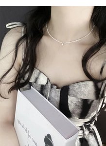 Dettaglio macro della collana di perle in argento 925 con pendente a stella su modella