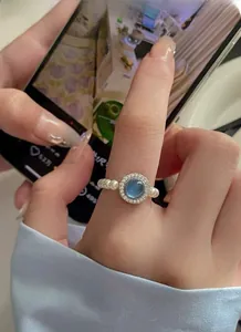 Detail of S925 silver ring featuring blue gemstone with pearl band on a finger