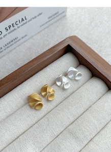 Detailed view of matte gold and silver spiral stud earrings in a velvet jewelry box