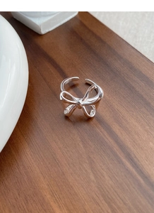 Detailed view of an S925 sterling silver bow ring with polished finish on wooden texture