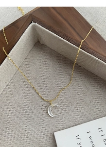 Macro detail of gold S925 silver necklace with moon pendant and white mother of pearl