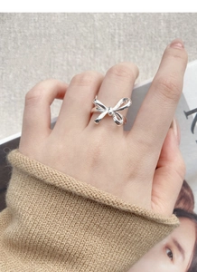 Silver bow knot ring shown on model's finger with a soft and stylish aesthetic