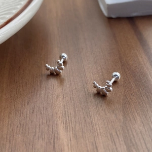 Cute S999 silver croissant stud earrings with beaded arc design on a wooden desk