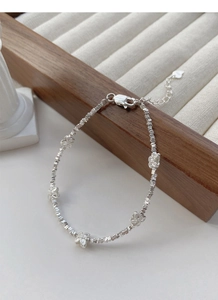 Detailed macro view of S925 sterling silver butterfly charms and faceted beads on a bracelet