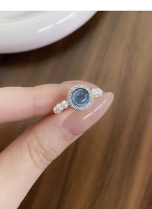 Close-up of S925 silver ring featuring blue gemstone and white pearl beaded band