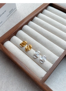 Detailed macro of gold and silver matte ruffled stud earrings in a jewelry display box