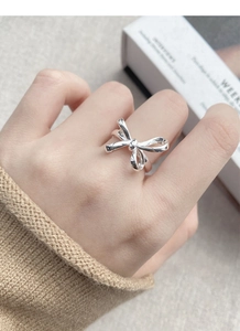 Detailed view of an S925 sterling silver bow ring with polished finish on model's finger