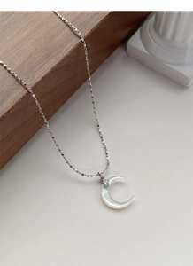 Macro shot of S925 sterling silver crescent moon pendant with shimmering white mother of pearl