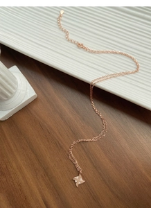 Detailed view of rose gold windmill necklace with zircons on white ceramic plate