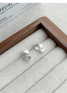 Detail of S925 sterling silver ruffled earrings with elegant matte metallic texture