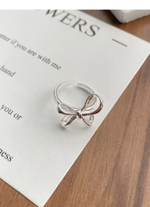 Close-up of S925 sterling silver bow ring with polished finish on a wooden surface