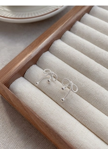 Detailed view of silver bow stud earrings with twisted texture in a premium gift box