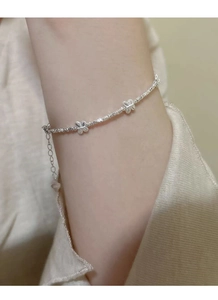 Detail showing S925 silver butterfly charms and beaded bracelet texture on wrist