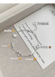 Detail of S925 sterling silver bracelet featuring charms of croissant, pretzel and donut
