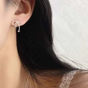 Elegant S925 sterling silver asymmetrical bow twist stud earring worn by a model