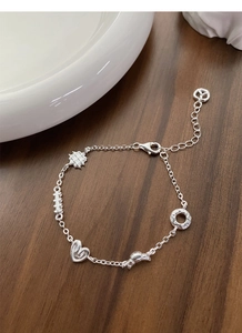 Detailed macro view of S925 silver charm bracelet with heart and bow pendants on wood