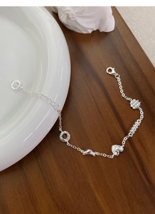 Detail of S925 silver bracelet featuring pretzel and donut charms with adjustable lobster clasp