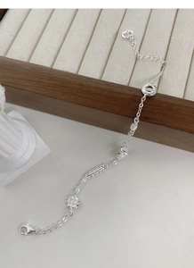 Macro detail of S925 silver bracelet featuring geometric charms and adjustable lobster clasp
