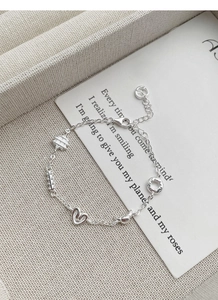 Macro shot of S925 sterling silver bracelet featuring heart and star charms with fine link chain
