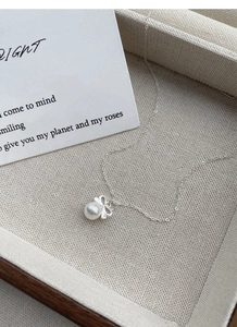 Détail du pendentif nœud en argent S925 avec perle blanche sur une chaîne délicate