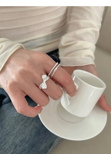 Detail of silver S925 bow, twisted and wavy stackable rings set worn by a model