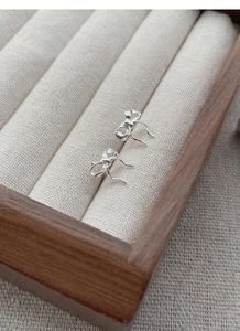 Close-up of silver bow stud earrings resting in a premium wooden jewelry display box