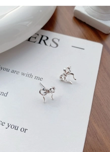 Macro detail of S925 sterling silver ribbon bow earrings with delicate hanging streamers