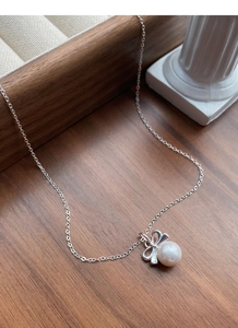 Vue détaillée du collier perle noeud argent sur bois avec décorations élégantes