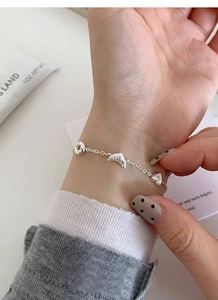 Detail of S925 silver bracelet featuring realistic croissant and heart-shaped charms on wrist