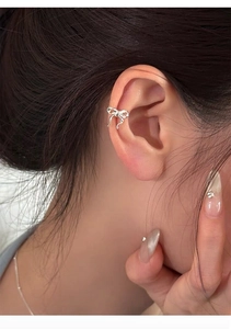 Detailed close-up of a silver bow-shaped ear cuff worn on the upper ear bone
