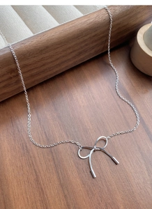 Macro detail of S925 sterling silver bow pendant necklace on dark wooden background