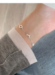 Macro detail of S925 silver bracelet featuring pretzel and croissant charms on wrist