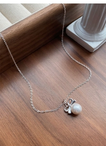 Vue macro d'un pendentif nœud en argent S925 avec perle blanche sur collier élégant