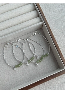 Detailed macro view of S925 silver beaded bracelets with green jade and lotus pod charms