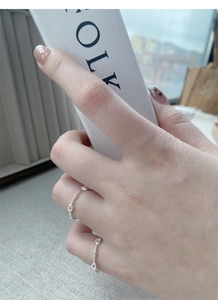Detail of two minimalist S925 sterling silver hollow heart rings on a model's hand