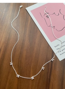 Close-up of S925 sterling silver necklace with five delicate cherry pendants on wood surface