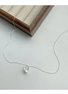 Détail du collier en argent S925 avec nœud et perle sur un plateau à bijoux élégant