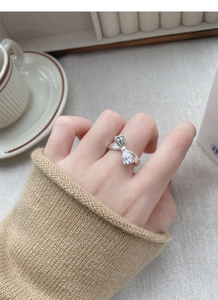 Macro shot of silver bow ring featuring textured surface on model finger
