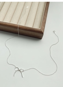 Macro detail of S925 sterling silver bow pendant and necklace chain with silver hallmark