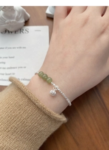 Detail of S925 sterling silver bracelet featuring green jade beads and a lotus seed pod charm
