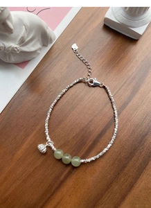 Macro detail of S925 silver bracelet with lotus charm and green jade beads