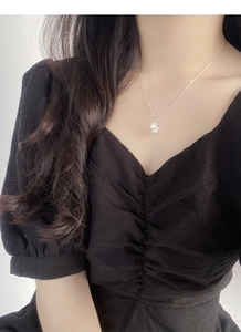 Détail d'un collier avec nœud et perle élégante porté sur une robe noire à col en V