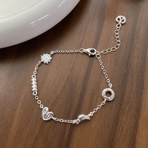 S925 Sterling silver bracelet featuring heart and geometric pendants on a wooden table