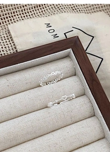 Close-up of S925 sterling silver hollow heart rings on a beige velvet jewelry box tray